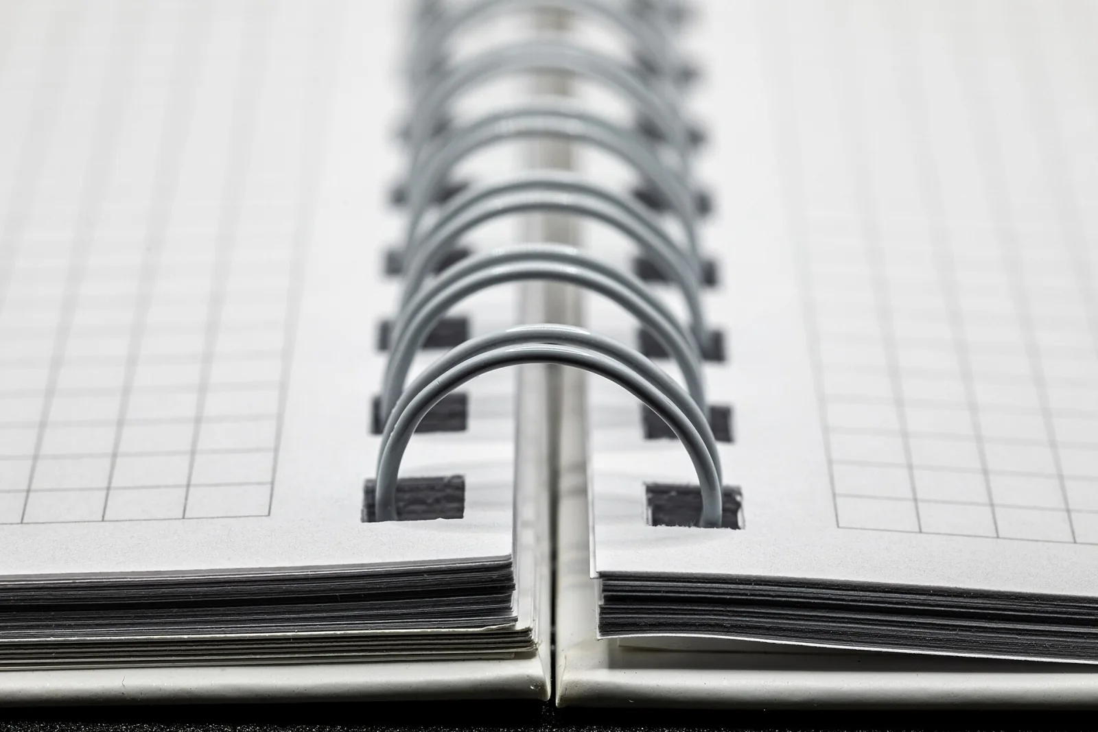 Gros plan de la spirale d'un cahier avec des pages à quadrillage vierges.