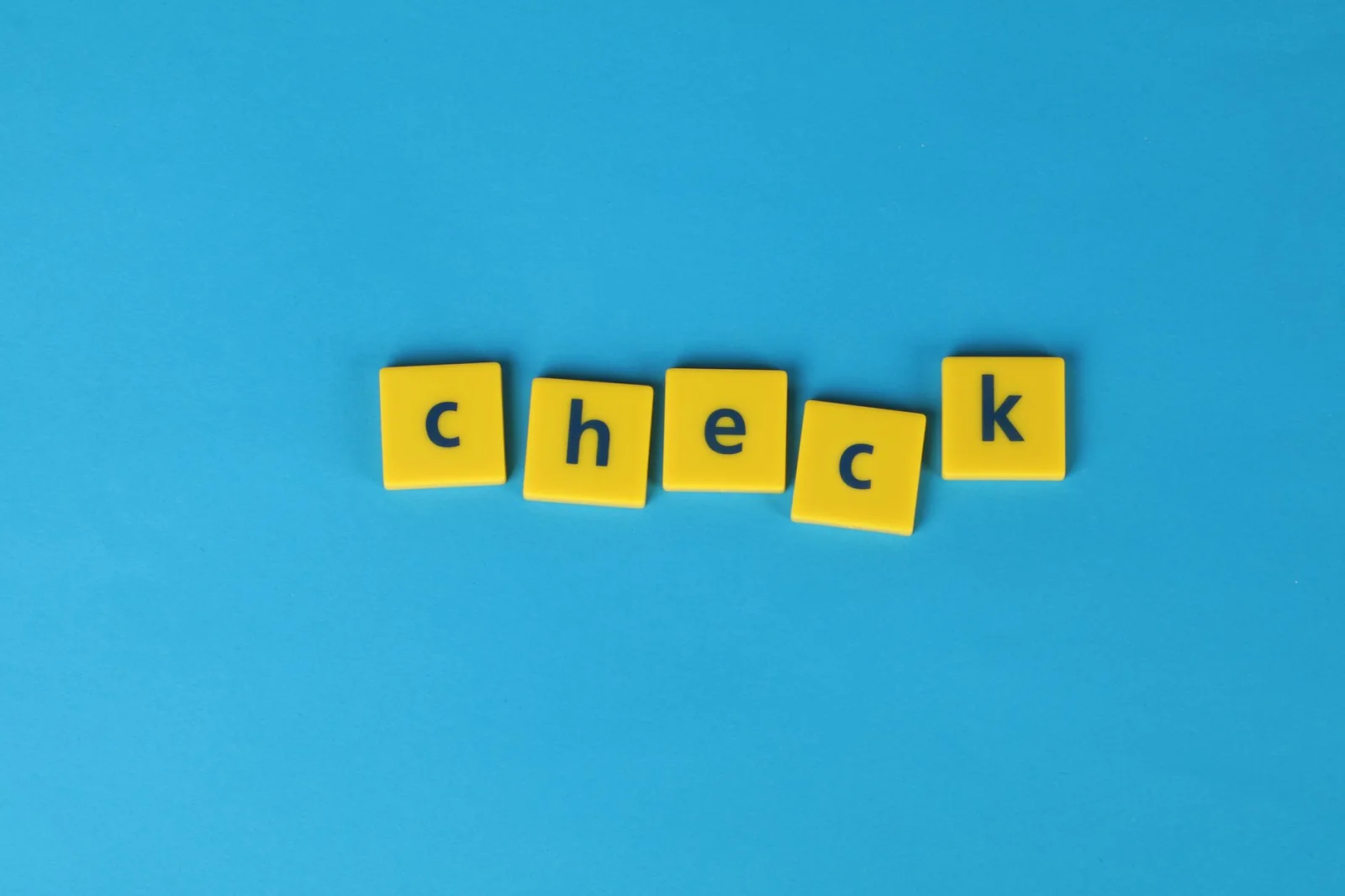 Des jetons jaunes avec les lettres formant le mot 'check' sur un fond bleu vif.