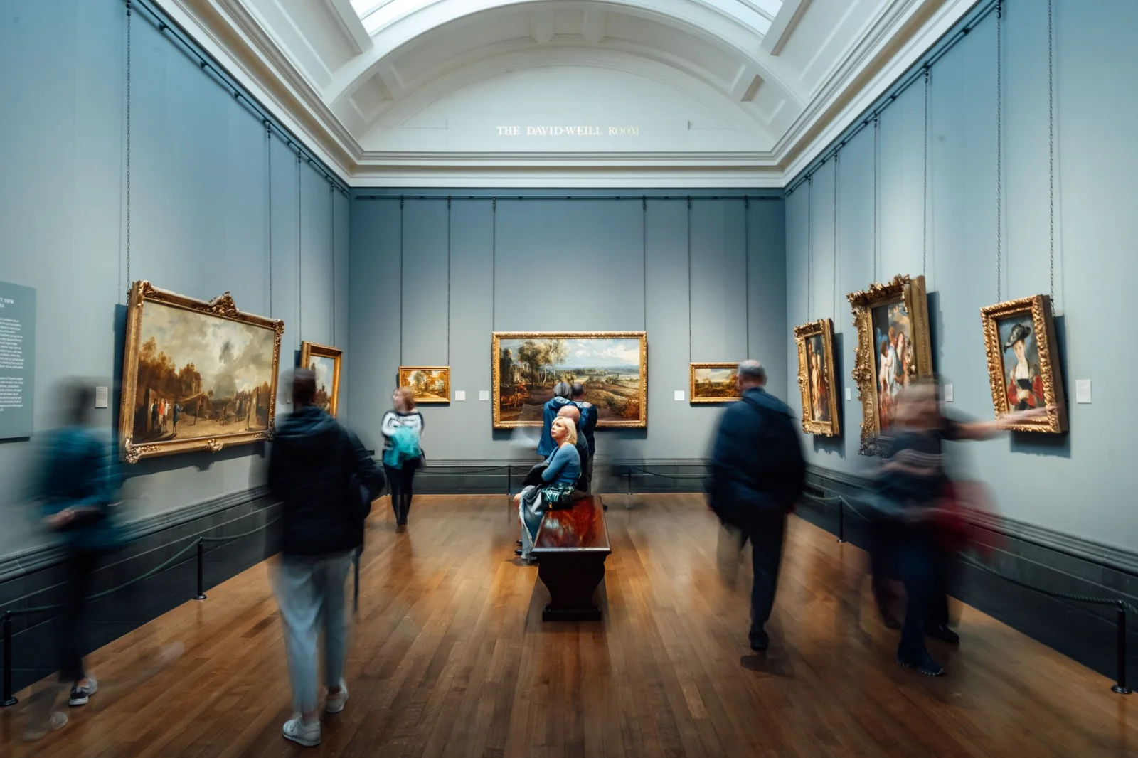 Visitors in an art gallery room called 'The David-Weill Room' admiring framed paintings in England.