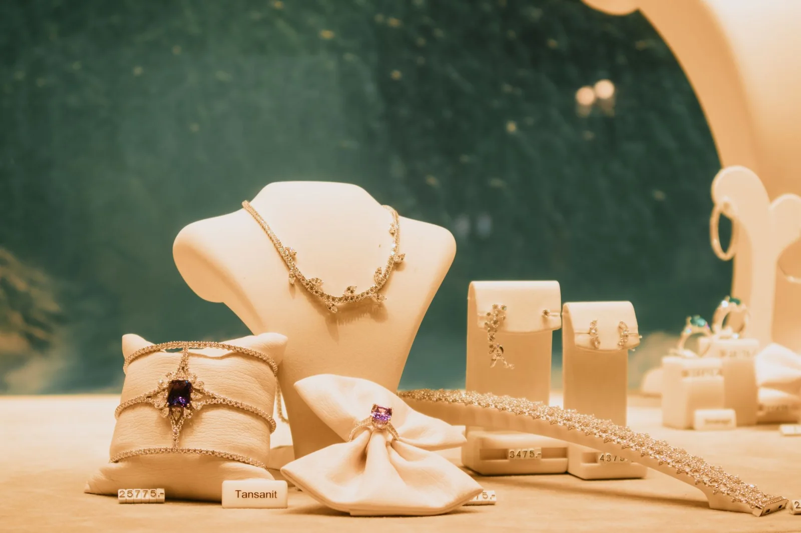 Conjunto de joias de luxo elegantemente exibido com colares, anéis e brincos em uma vitrine de loja.
