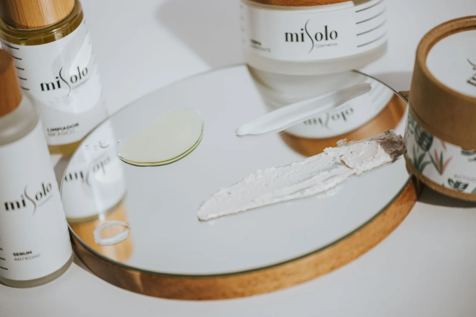 Disposición estética de productos cosméticos en un espejo con la luz del sol resaltando texturas.