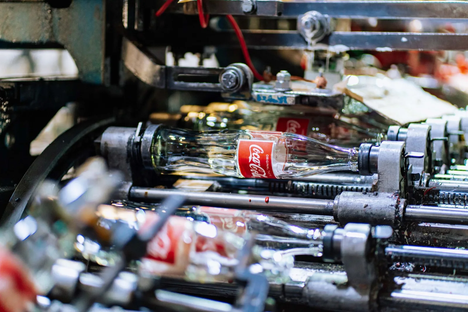 Garrafa de vidro de alta qualidade, incluindo uma garrafa de Coca-Cola, sendo processadas numa linha de produção de fábrica.