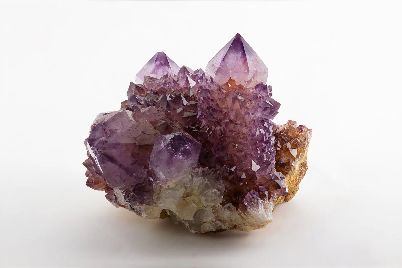 Amethyst specimen from Magaliesburg, South Africa showing purple crystals on rocky matrix against a white background.