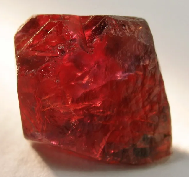 Conceptual image of a rough ruby crystal, shown in deep red tones, with irregular surface and translucent texture.