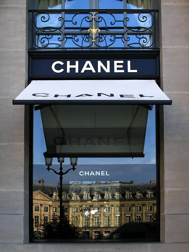 Façade de la boutique Chanel Joaillerie à la Place Vendôme, Paris, avec le logo Chanel visible et le reflet du bâtiment en face dans la vitrine.