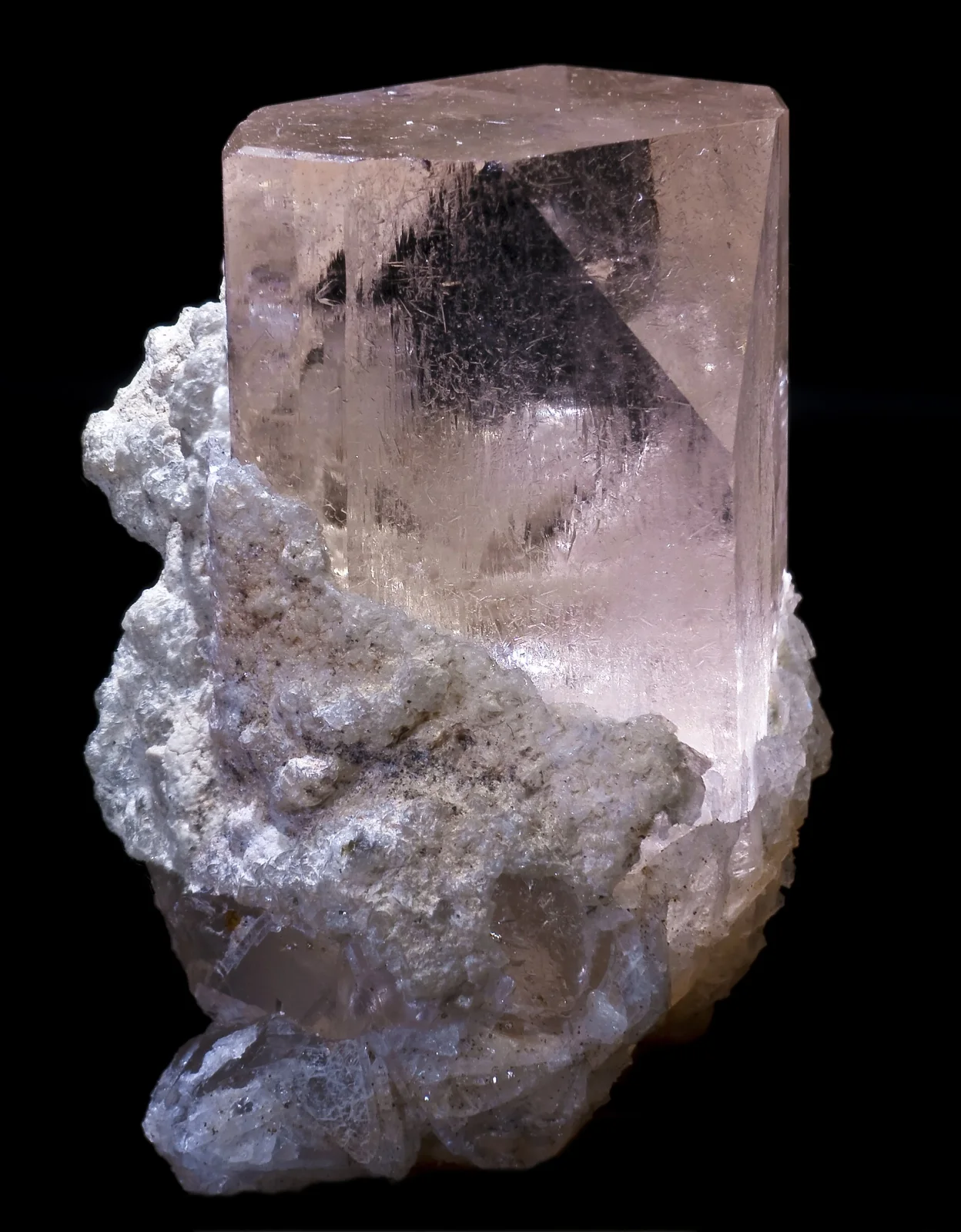 Medium-sized pink topaz crystal mounted on white mineral matrix, against a black background.