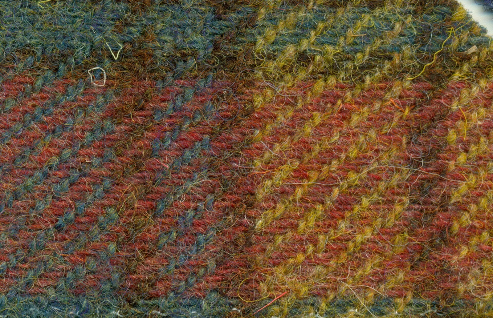 Conceptual image of a close-up of Harris Tweed woven fabric featuring diagonal lines and a checkered pattern in brown, red, blue, and yellow colors.