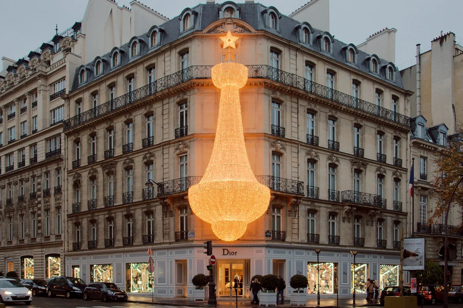 Imagen conceptual de la tienda Dior en 30 Avenue Montaigne en París, Francia, con decoración iluminada en forma de estrella y lámpara gigante en la fachada del edificio histórico.