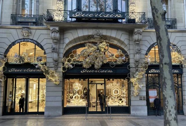 Weihnachtsfenster der Guerlain-Boutique auf den Champs-Élysées mit goldenen Dekorationen und festlichen Lichtern.