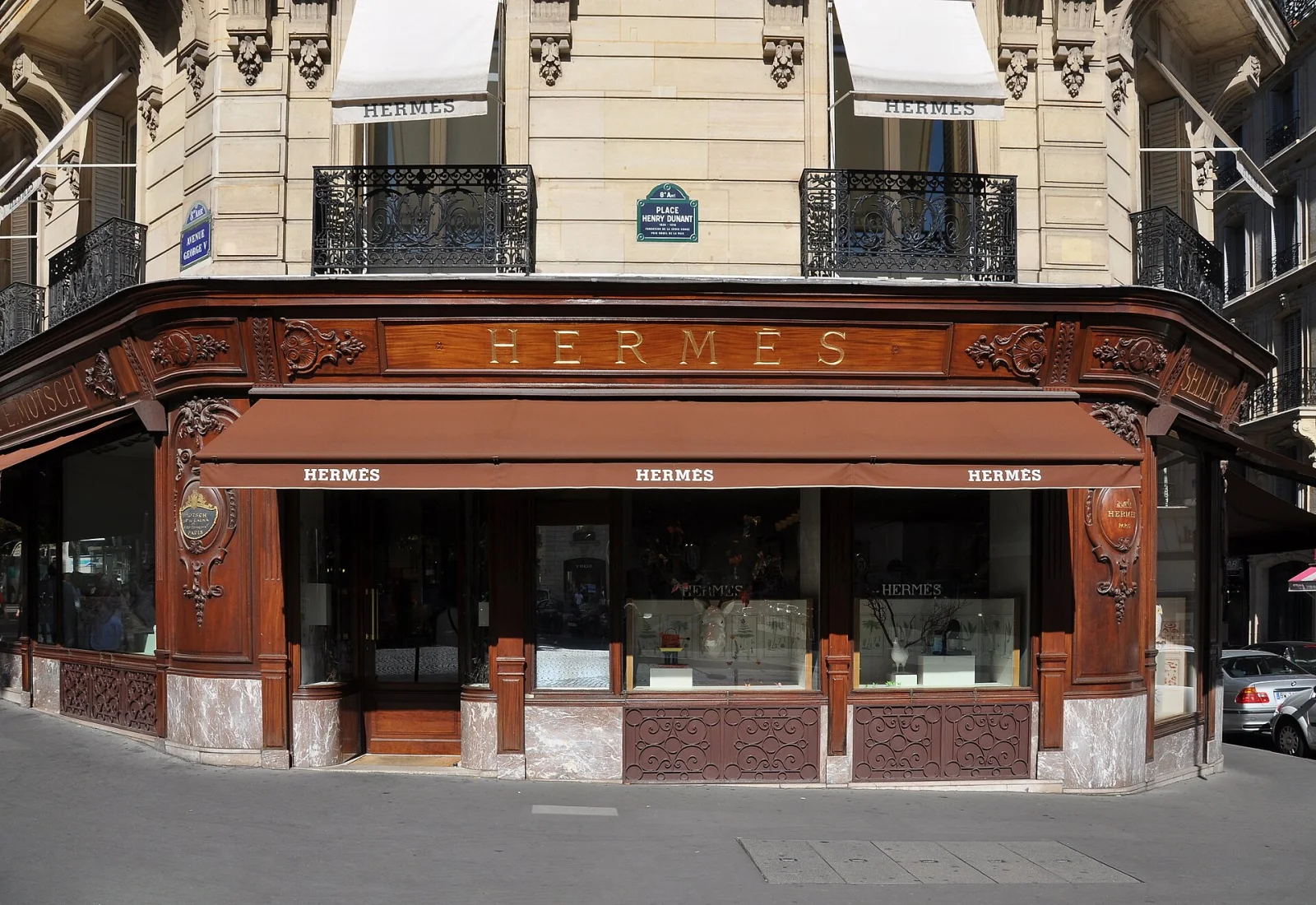 Facciata di un negozio Hermès in Avenue George V, Parigi, con tende da sole e dettagli in legno intagliato.